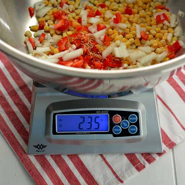 Metal bowl with corn kernels and some other ingredients on top of the MyWeigh KD-8000 and the monitor showing "235". | MakeSauerkraut.com